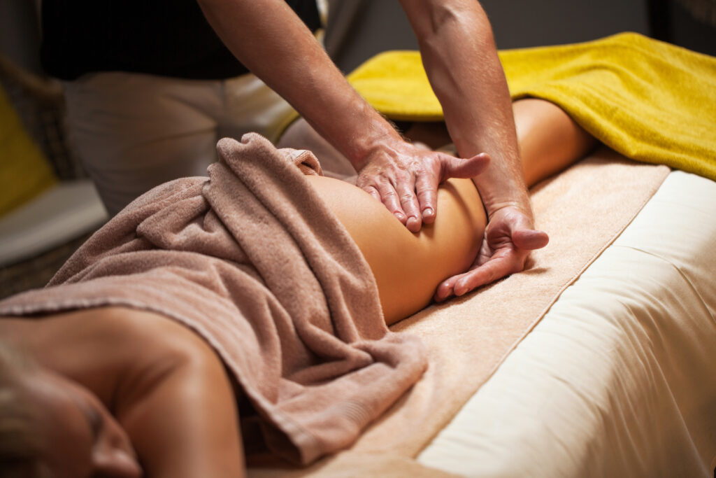 Eine Person erhält auf einem Massagetisch eine Beinmassage.