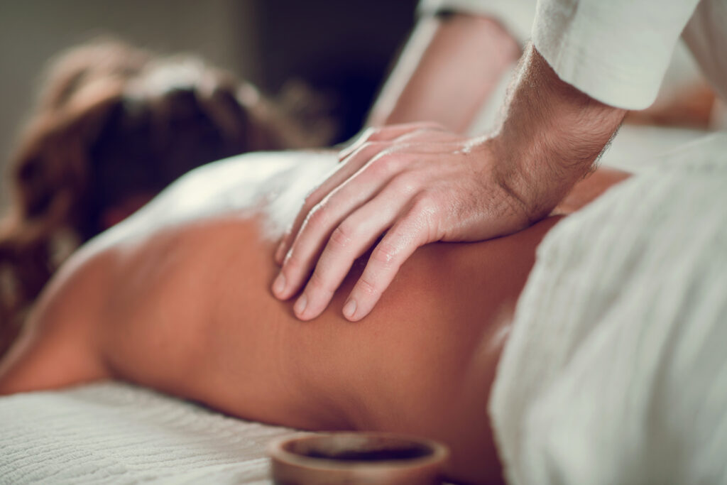 Eine Person erhält eine Rückenmassage, wobei der Schwerpunkt auf den Händen der Masseurin liegt.